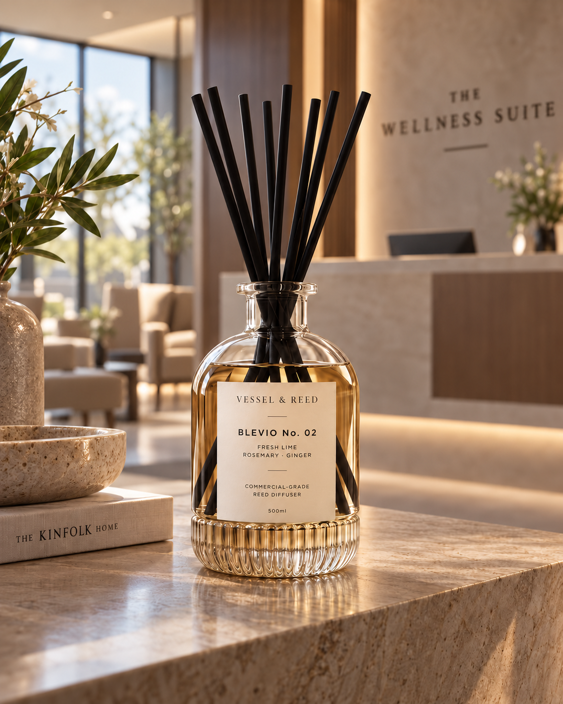 The Vessel & Reed Blevio No. 02 diffuser — fluted glass vessel with black fibre reeds — on a stone counter in a wellness suite reception