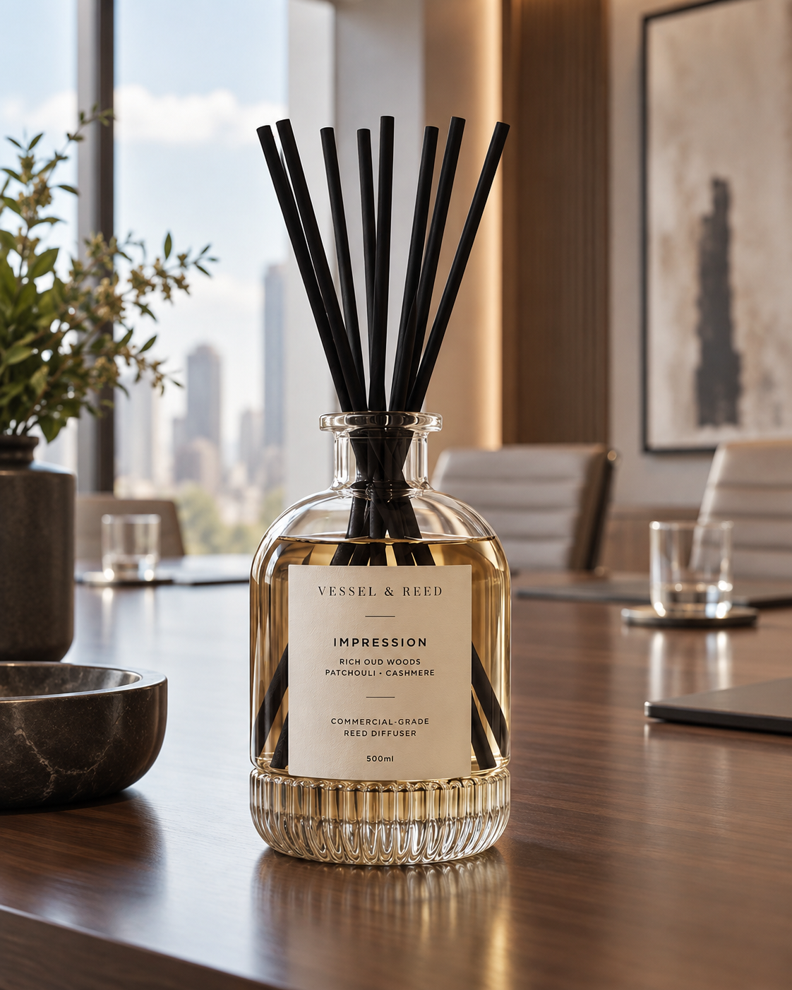 The Vessel & Reed Impression diffuser — fluted glass vessel with black fibre reeds — on a boardroom table