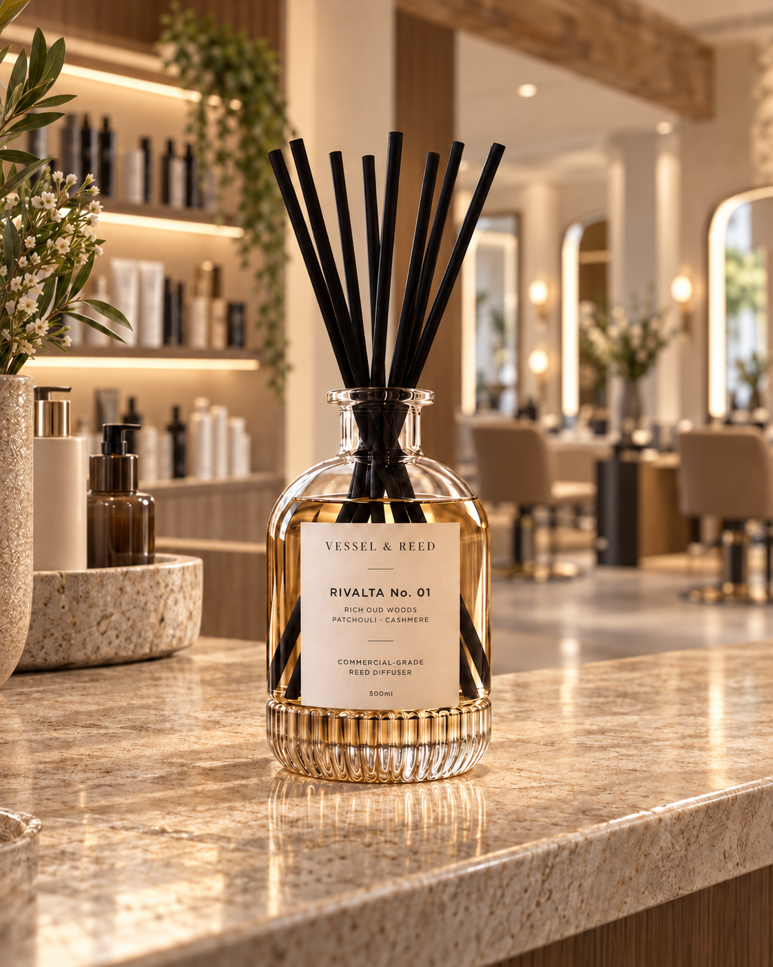 The Vessel & Reed Rivalta No. 01 diffuser — fluted glass vessel with black fibre reeds — on a marble counter in a hair salon reception